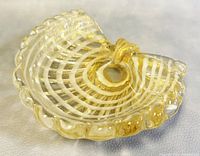 Front angle view showing the clam shell shape, gold flecks embedded in clear glass, and scalloped edges.