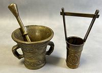 Both items displayed side by side on a gray surface showing the brass mortar and pestle next to the miniature brass pail.