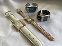 Top view of four women's watches on white background showing face and bands