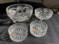 Four crystal bowls on dark surface showing pinwheel cut pattern and Natchmann stickers on two smaller bowls