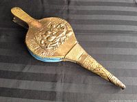Top side view showing embossed brass top with ornate design and blue leather sides