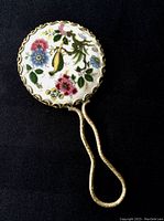 Front view showing porcelain back with colorful floral decoration on the round mirror.