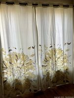Full view of two white curtain panels hanging on rod, showing large yellow floral pattern on lower part of panels