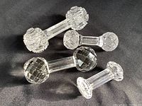 Four antique/vintage crystal cutting utensil rests displayed on black fabric. Includes diamond cut end design and Imperial Nucut dumbbell style rests.