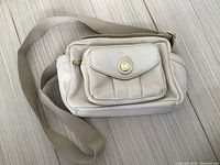 Front view of the Michael Kors ivory white shoulder purse, displaying the front flap pocket with MK logo button and beige strap.