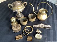 Assortment of brass items including a sugar bowl, teapot, cups, incense burners, pill containers, brass Scottie dog figurine, rings, and decorative bar