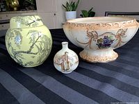 Front view of the urn, miniature vase, and fruit bowl arranged on black cloth, showing design details and relative sizes