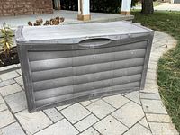 Closed view of gray plastic outdoor storage box with wood-grain texture, rectangular shape, and side handles.