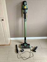Assembled vacuum upright with floor nozzle and handle, accessories and charger laid out on floor