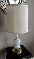 Full photo of vintage white glass table lamp with floral hand-painted design, brass base, and white fabric lampshade.