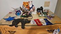 Photo showing assortment of glass paperweights including fish and starfish, stained glass butterfly lamp, ceramic lion and cat banks, small animal figurines in various materials.