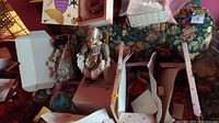 Overview photo showing multiple dolls in original boxes placed on floral patterned fabric