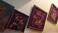 Needlepoint artworks with Asian figures and fish theme framed on a wall