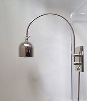 Chrome wall mount lamp shown off with visible curved arm and dome shade, mounted on a white wall
