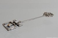 Side angle showing textured brutalist pendant and attached chain.