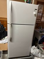 Front view showing entire white Kenmore refrigerator with top freezer and bottom fridge door, with vertical handles on left side.