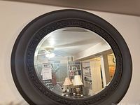 Front view of round wall mirror with wood frame and carved decorative pattern.