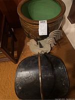 Photo showing ceramic planter with green interior, decorative metal rooster, and metal firewood carrier with brass handle, all on carpeted floor.