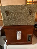 Closed Seabreeze portable record player in textured black and white carrying case with metal clasps on top of wooden entertainment center.
