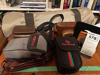 Four camera cases and canvas tripod bag on wooden table