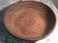 Top view of a round woven basket showing tight coil weaving and natural fiber color variations.