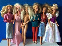 Full view of six vintage Barbies from 1966 in varying outfits against a blue background