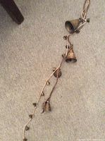 Photo of a string of small brass bells on a light carpet background showing the overall length and shape.