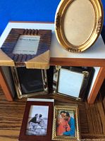 Photo showing six different smaller frames arranged on a wooden surface and a small wooden box, various shapes including oval and rectangular, with diverse frame finishes.