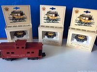 Three boxed HO scale vintage style stagecoach passenger train cars with the vintage red American Flyer caboose in front.