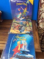 Three vintage Disney LaserDiscs displayed vertically showing Peter Pan, Jungle Book, and The Sword in the Stone covers.