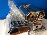 View of pasta machine partially wrapped in bubble wrap showing shiny stainless steel housing and hand crank