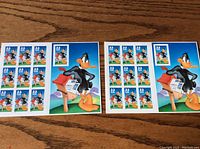Two full sheets of 33 cent Daffy Duck stamps on a wooden surface.