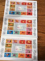Three sheets of postage stamps laid out on a wooden surface showing colorful illustrations of the twelve zodiac animals with decorative borders.