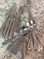 Two images showing two sets of vintage silverware: butter knives and spoons in very good condition, no forks included.