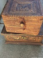 Close view showing wicker box on top of rustic wood box, highlighting the woven texture and keyhole detail on wooden box.
