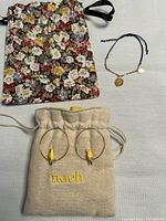 Full lot with floral pouch for bracelet and beige pouch for earrings visible, showing entire contents.