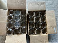 Two open cardboard boxes filled with clear glass canning jars, top view showing jars neatly arranged without lids.