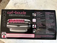 Box of Conair Curl Boucle heated hair curlers showing product features and technology including tourmaline ceramic coating, ion shine technology, 20 curlers and clips, and rapid heat in 75 seconds.