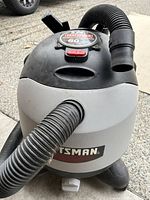 Front view of Craftsman ShopVac, showing the flexible hose attached and Craftsman branding on the unit