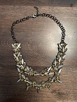 Full front view of the double-layered crystal necklace with silver-tone chain against a wooden surface.