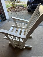 Full view of the white wooden glider chair showing its vertical slats and base rockers