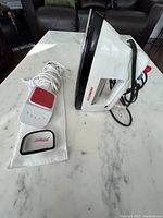 Sunbeam electric iron and fabric steamer with cord on marble surface