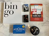 Five boxed games include Bingo, Game Pad multi-games, Anomia card game, Golf cards, and a black spinning top game.