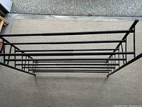 Top-down view showing the full five-tier structure of the black metal shoe rack on a beige carpet.