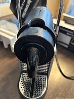 Front view of Nespresso Pixie machine showing capsule insertion area and chrome handle lever.