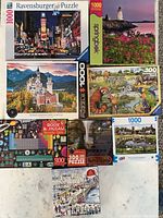 Photo showing all eight puzzles stacked in two rows on a flat surface, boxes visible with puzzle images and piece counts.