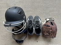 Softball helmet, children's cleats, and softball glove arranged on a white background.