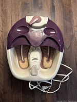Top-down view of Waterpik foot spa showing foot inserts, massaging rollers, pumice stone, and power cord
