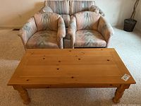 Photo showing two barrel arm side chairs with pastel geometric upholstery and a pine coffee table with natural finish front view