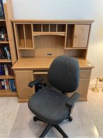 Photo of pine wood desk with hutch and gray rolling chair in front. Desk and hutch show natural wood grain and construction details.